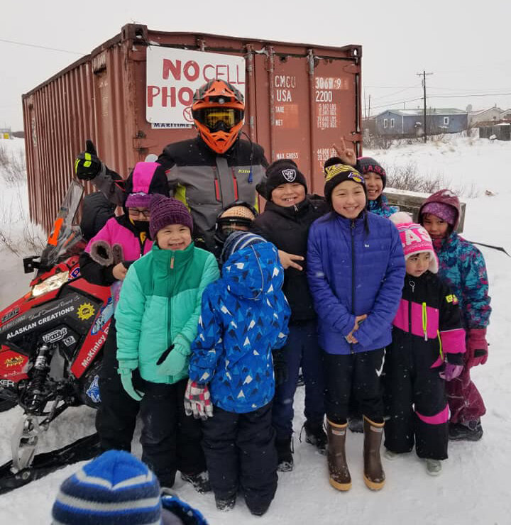 Team 21 stops for a photo op with the children in Buckland. Source: Iron Dog Facebook Group / Pep Sage