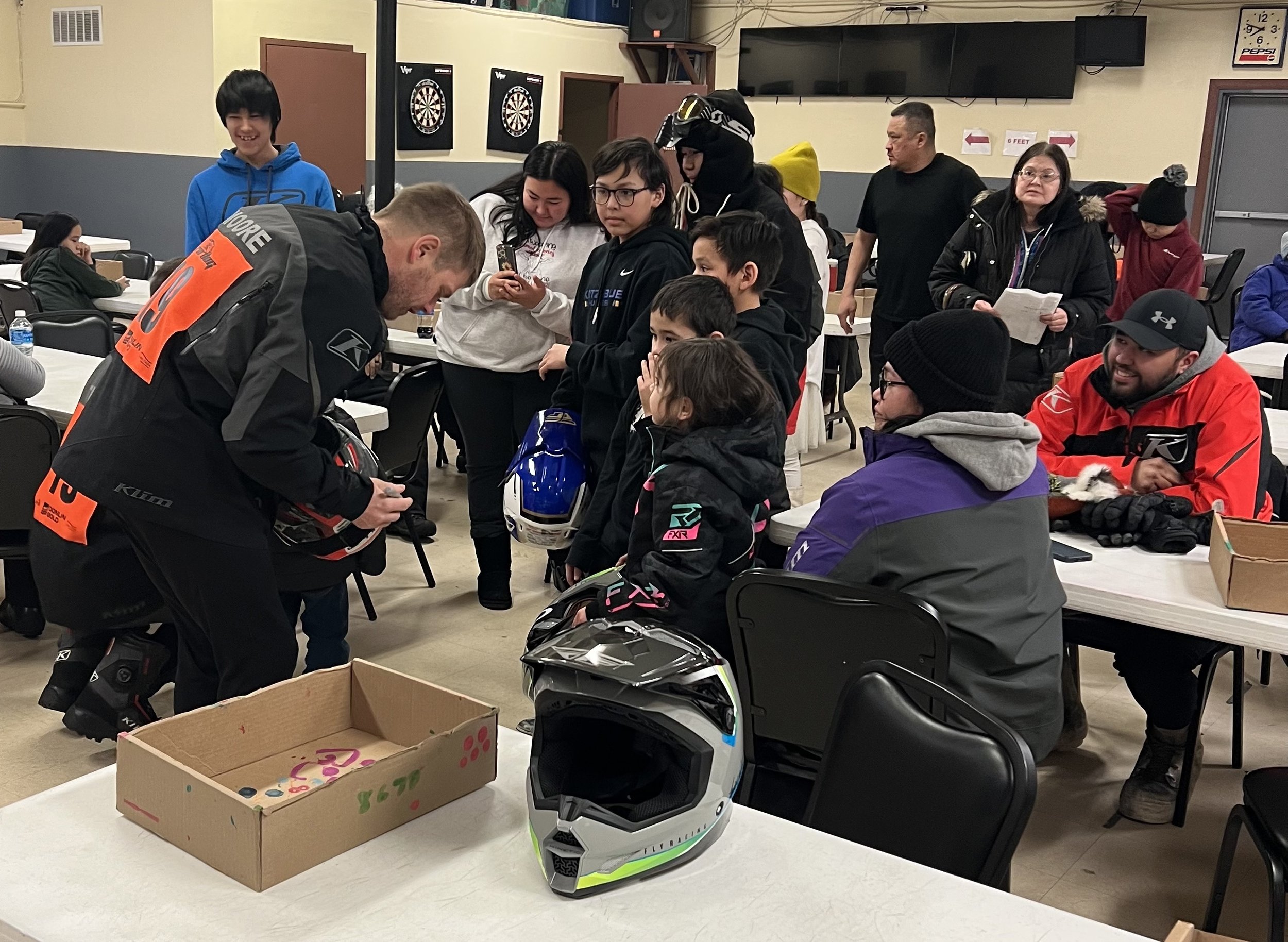 Team 19’s Chad Moore signs helmets for race fans during a meet and greet Sunday evening at the Kotzebue Lions Club. Johnny Dean photo