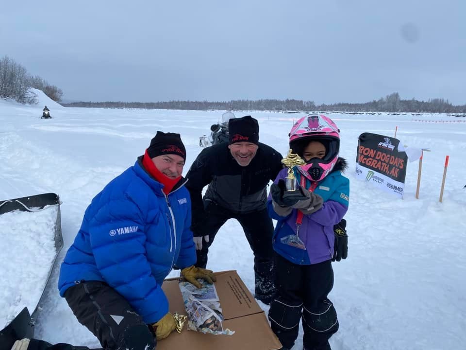 Shelborne Christopher took this photo of his daughter celebrating her prize after kids snowmachine races at the 2022 Iron Dog Days, presented by Donlin Gold, in McGrath. Iron Dog board members Doug Dixon, is at left, and Mike Vasser, middle.