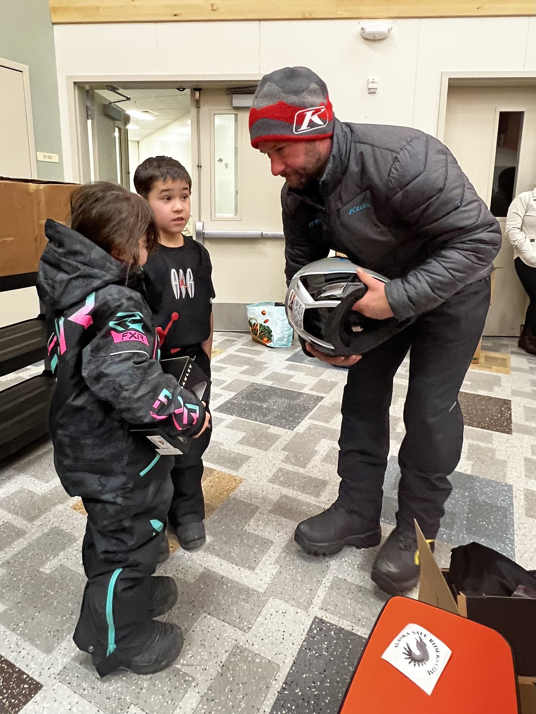 Ambassador Team 77 rider Roger Brown helps fit kids with properly sized helmets during Kotzebue’s helmet giveaway program. Courtesy Roger Brown